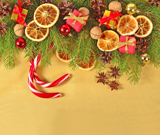 Dried oranges and cones Christmas decorations and spruse branch on a golden background