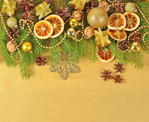 Dried oranges and cones Christmas decorations and spruse branch on a golden background