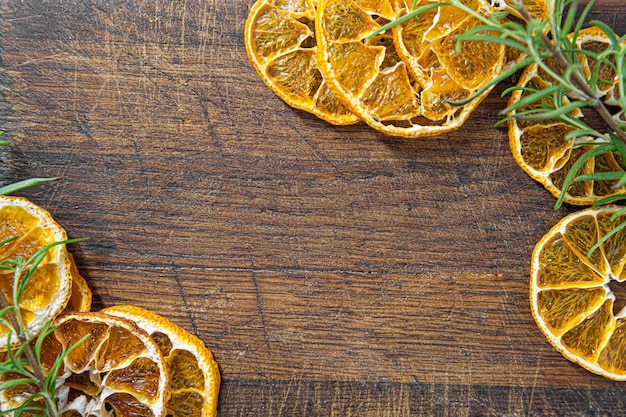 Dried oranges with basil leaves frame. Dried citruses on wooden background frame template. Copy space.