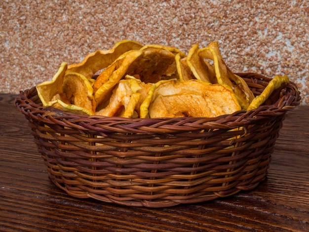 Dried organic apples in a wicker basket on wooden table