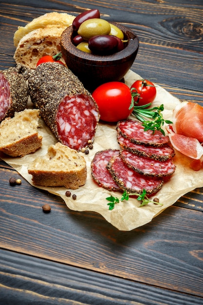 Dried organic salami sausage covered with pepper on wooden table