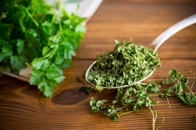 Photo dried parsley in a spoon next to fresh herbs