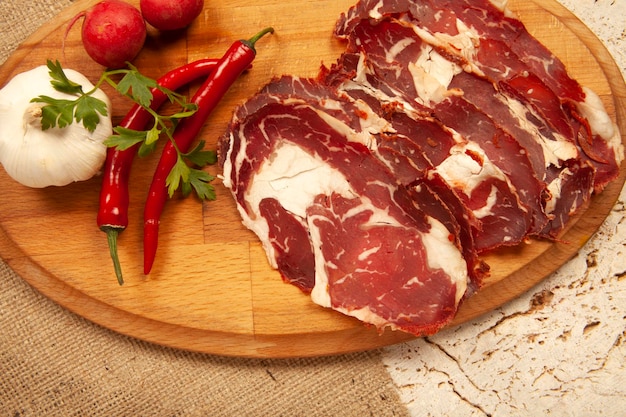 Dried pastrami slices on wooden board