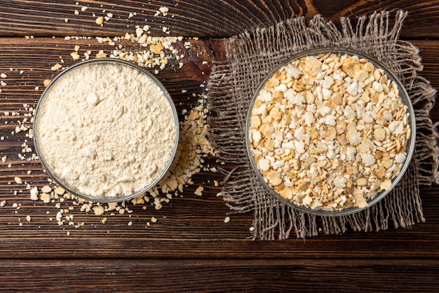 Dried pea flakes and flour on dark wooden