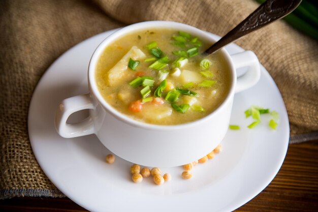 Суп из сушеного гороха в тарелке с травами на деревянном столе