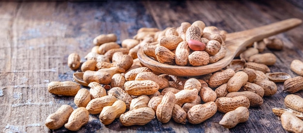 Dried peanuts or nuts on wooden backgroundPeanut shells on a wooden spoon