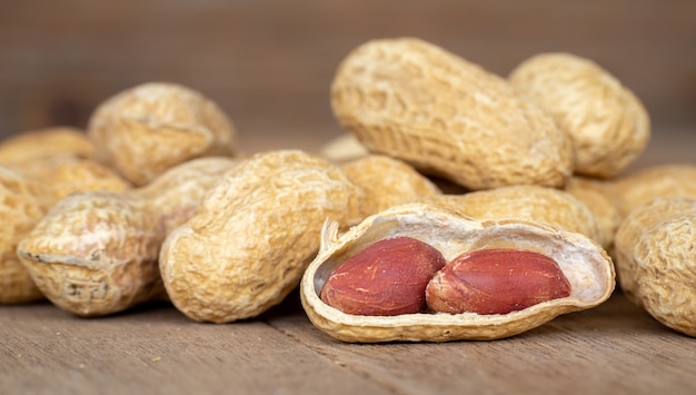 Dried peanuts in shells on peanuts background on wooden table. Concept of snack