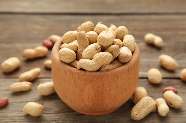 Dried peanuts in wooden bowl on grey background.