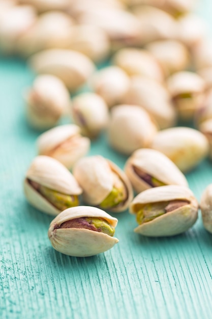 Photo dried pistachio nuts on green wooden table pistachio kernel