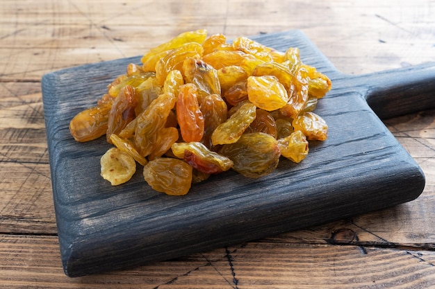 Dried raisins from white grapes on a wooden chopping board