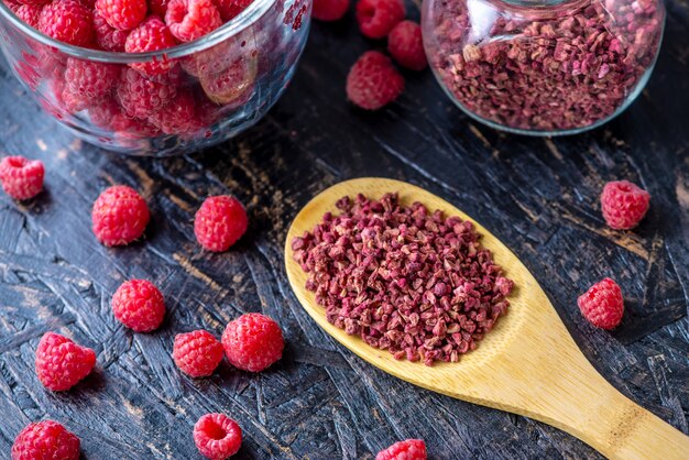 Dried raspberries in a glass jar and a wooden spoon