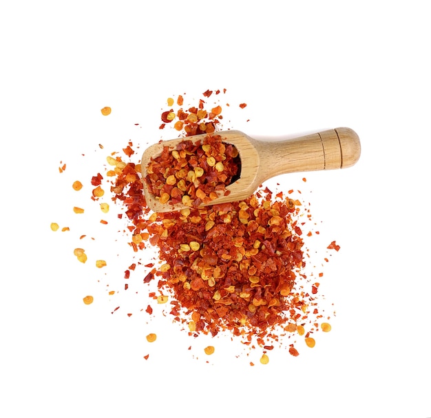 Dried red chili pepper flakes in wooden scoop isolate on white background