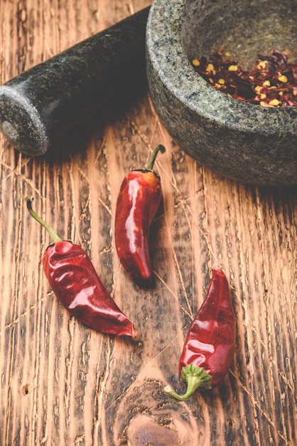 Dried red chili peppers on wooden surface with mortar and pestle