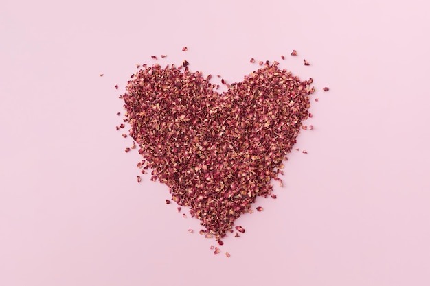 Photo dried red rose petals in shape of heart