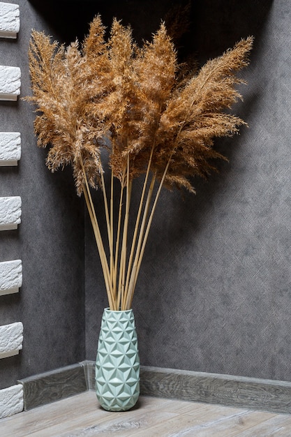 Dried reeds as home decor. Minimalistic cozy interior. Natural interior. Still life with a reed. Grass for interior design