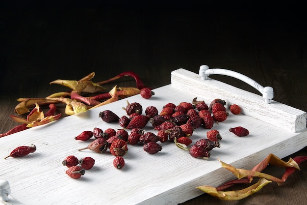 Dried rose hips and apples on a white painted tray