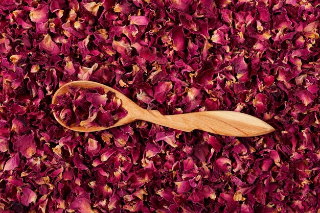 Dried rose petals as background purple rose flowers in wooden
spoon closeup