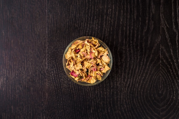 Dried rose petals in a glass bowl on black background. Used for perfumes, cosmetics, teas and baths. Close up. Still life