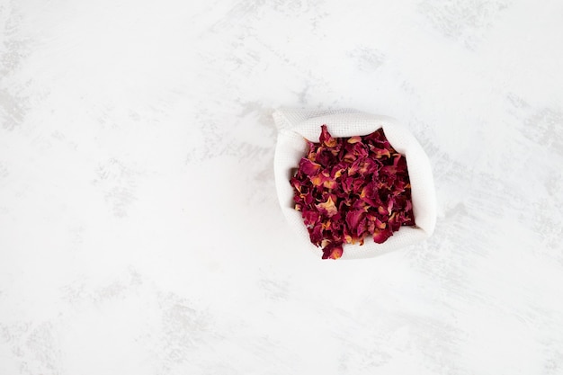 Dried rose petals in white pouch top view Selective focus copy space