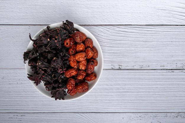 Photo dried roselle flower buds and dried jujube on white wood red roselle can make healthy beverage