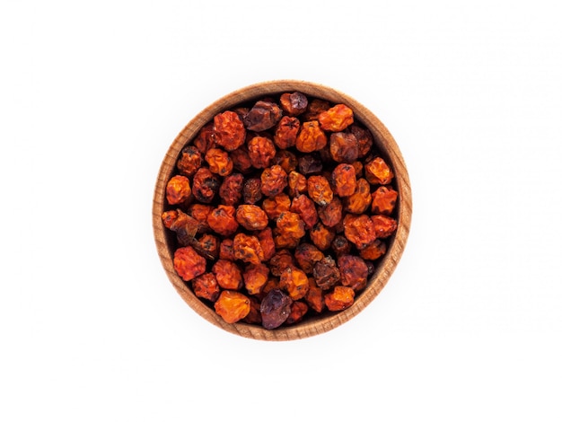 Dried Rowan or Sorbus berries in a wooden Cup on a white 