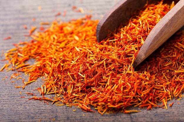 Dried saffron spice in a spoon on wooden table