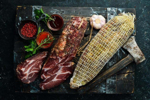 Dried and salted piece of meat Prosciutto jamon on a black stone background Top view Free space for text