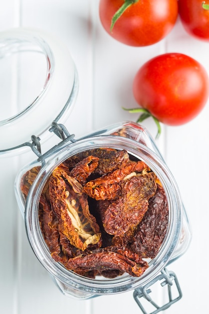 Photo dried sliced tomatoes in jar and fresh tomatoes tomatoes as superfood top view