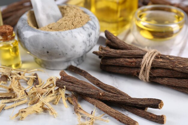 Photo dried sticks of licorice roots shavings and powder on white table closeup