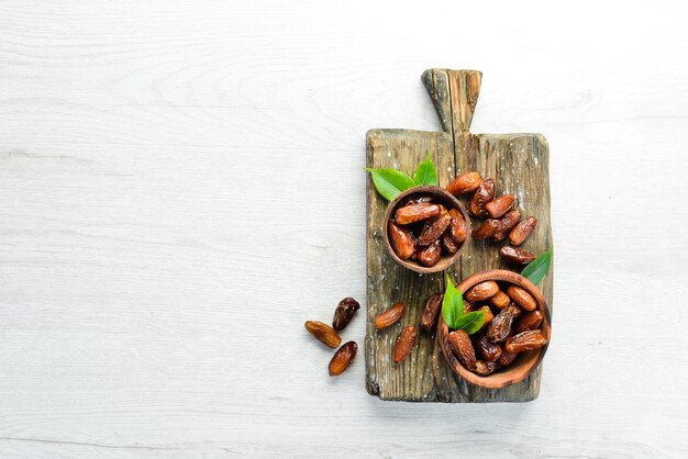 Dried sweet dates on white wooden background.