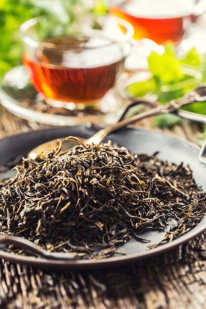 Photo dried tea leaves in bowl on rustic wooden table