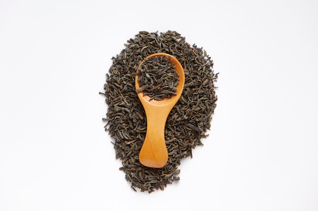 Dried tea leaves on a wooden spoon isolated . top view