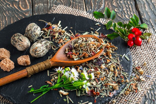 Dried tea leaves on a wooden spoon on an old table.