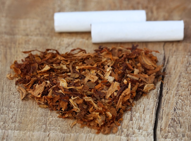 Photo dried tobacco leaves and cigarette decorated in heart shape