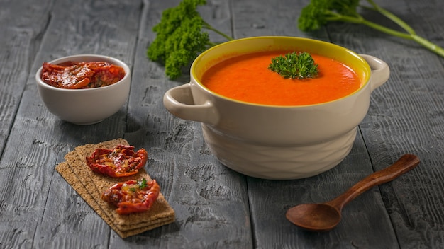 Dried tomatoes and mashed bell pepper soup on a wooden table