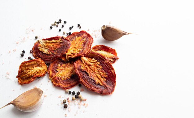 Dried tomatoes with black pepper and garlic on a white background