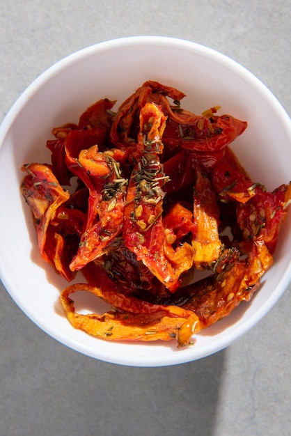 dried tomatoes with spices in a white plate on a gray concrete background