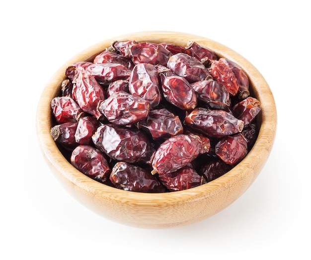 Dried wild rose berries in wooden bowl isolated on white background with clipping path