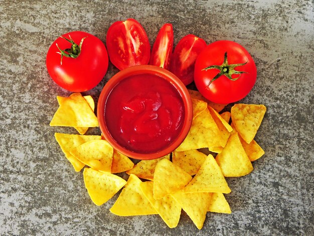 Driehoekige gele chips en rode saus met tomaten