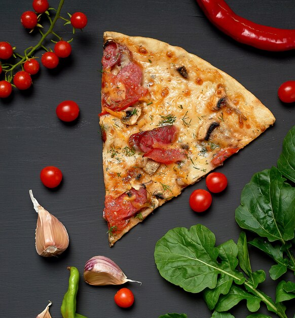 Driehoekige plak gebakken pizza met champignons, gerookte worstjes, tomaten en kaas