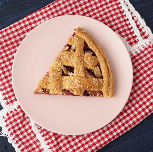 Driehoekige segment van gebakken cherry pie op een roze ronde plaat
