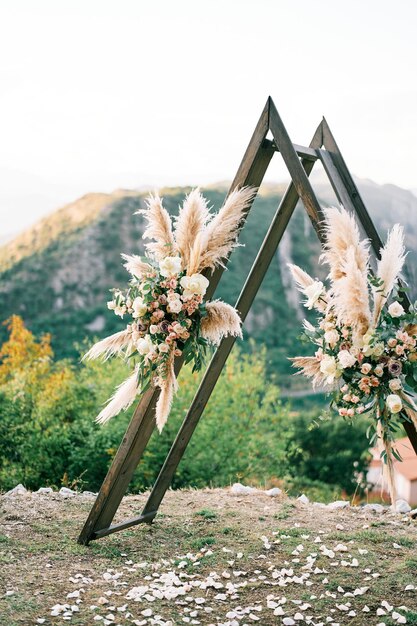 Foto driehoekige trouwtipi boog versierd met bloemen staat op een berg