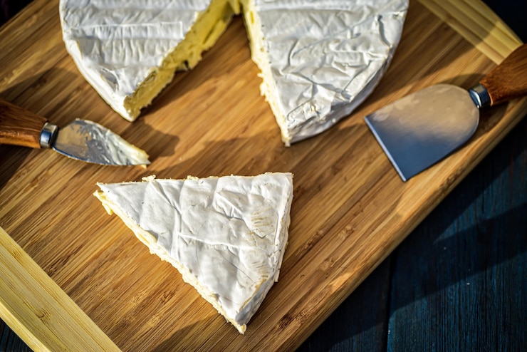 Foto driehoekige wig van brie kaas gesneden uit een hele ronde op een bamboe snijplank