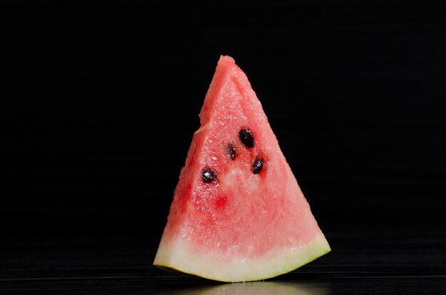 Driehoeks rijpe watermeloen op een zwarte achtergrond