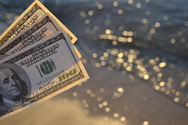 Driehonderd-dollarbiljetten op de achtergrond van de contante dollar van het zeeoppervlak