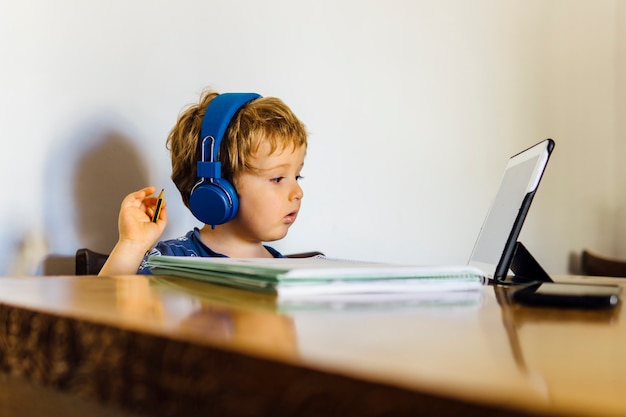 Driejarige jongen die een online klas bijwoont op school die thuis met de tablet naar de media kijkt