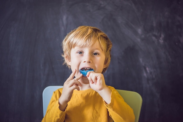 Driejarige jongen toont myofunctionele trainer. Helpt bij het egaliseren van de groeiende tanden en de juiste beet, het ontwikkelen van mondademhaling. Corrigeert de positie van de tong