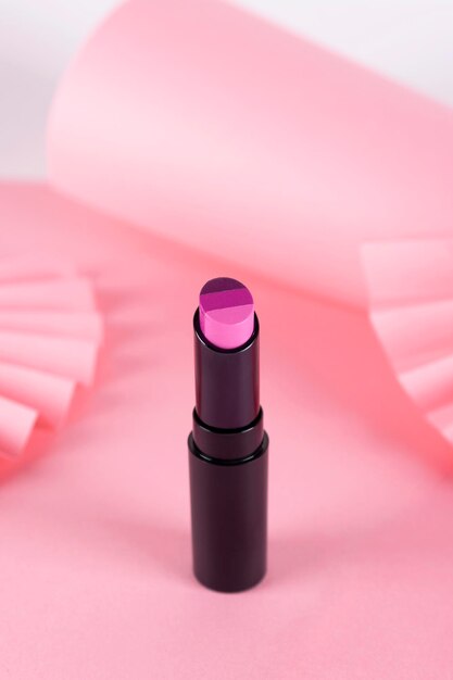 Driekleurige lipstickxALipstick liggend op een roze achtergrond