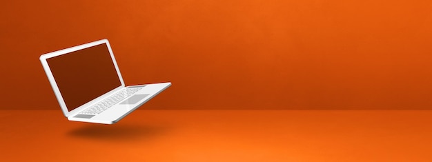 Foto drijvende computerlaptop die op oranje wordt geïsoleerd horizontale bannerachtergrond