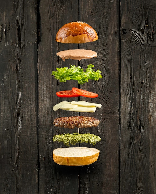 Drijvende pestoburger ingrediënten op de houten muur
